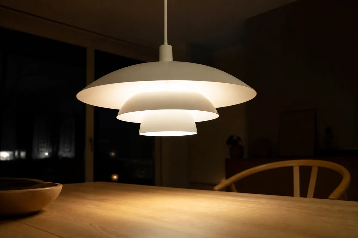 Suspension à trois abat-jour en métal blanc au-dessus d une table en bois clair