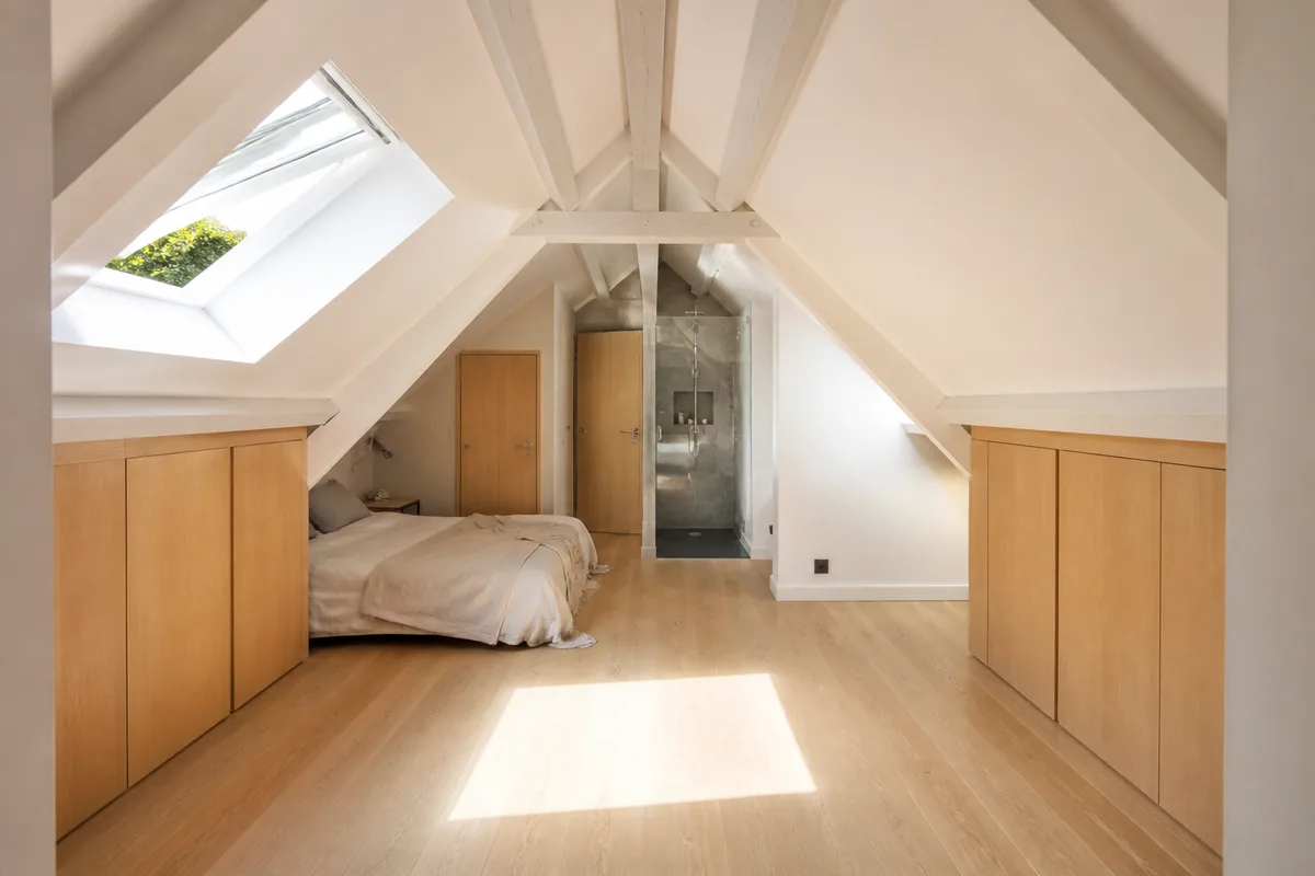 Combles aménagés en chambre sous rampants avec fenêtre de toit ouverte